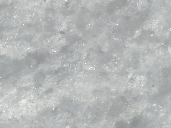 Rough ice texture, made up of bright white snow and dark, reflective chunks of ice.